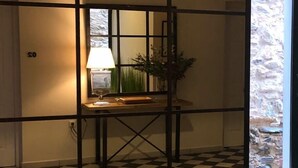 A room with a checkered floor, a black metal partition, and a table with a lamp and plants. - Hotel La Muralla (Zafra)
