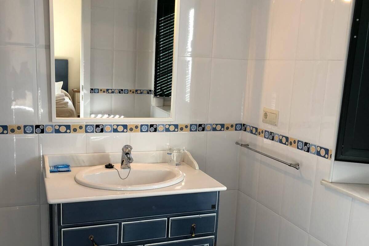 Ein Badezimmer mit einem weißen Waschbecken, dunkelblauen Schränken und einem Spiegel über dem Waschbecken.