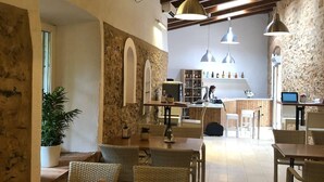 A restaurant with wooden beams, stone walls, and wicker furniture. - Hotel La Muralla (Zafra)