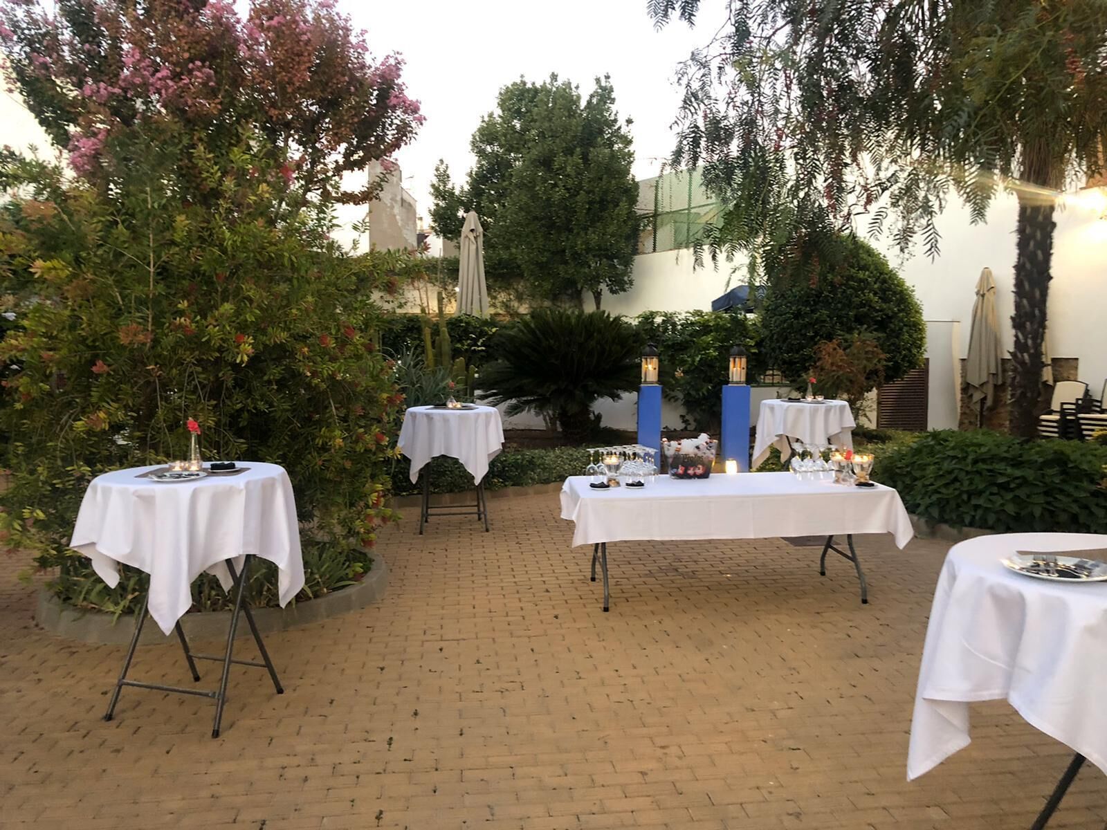 An outdoor patio with tables set up for dining, surrounded by lush greenery and trees.
