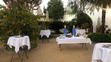 An outdoor patio with tables set up for dining, surrounded by lush greenery and trees.