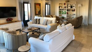A modern living room with a white sofa, striped armchairs, a coffee table, and a bookshelf. - Hotel La Muralla (Zafra)
