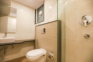 Uma casa de banho moderna com sanita branca, lavatório e cabine de duche em vidro.