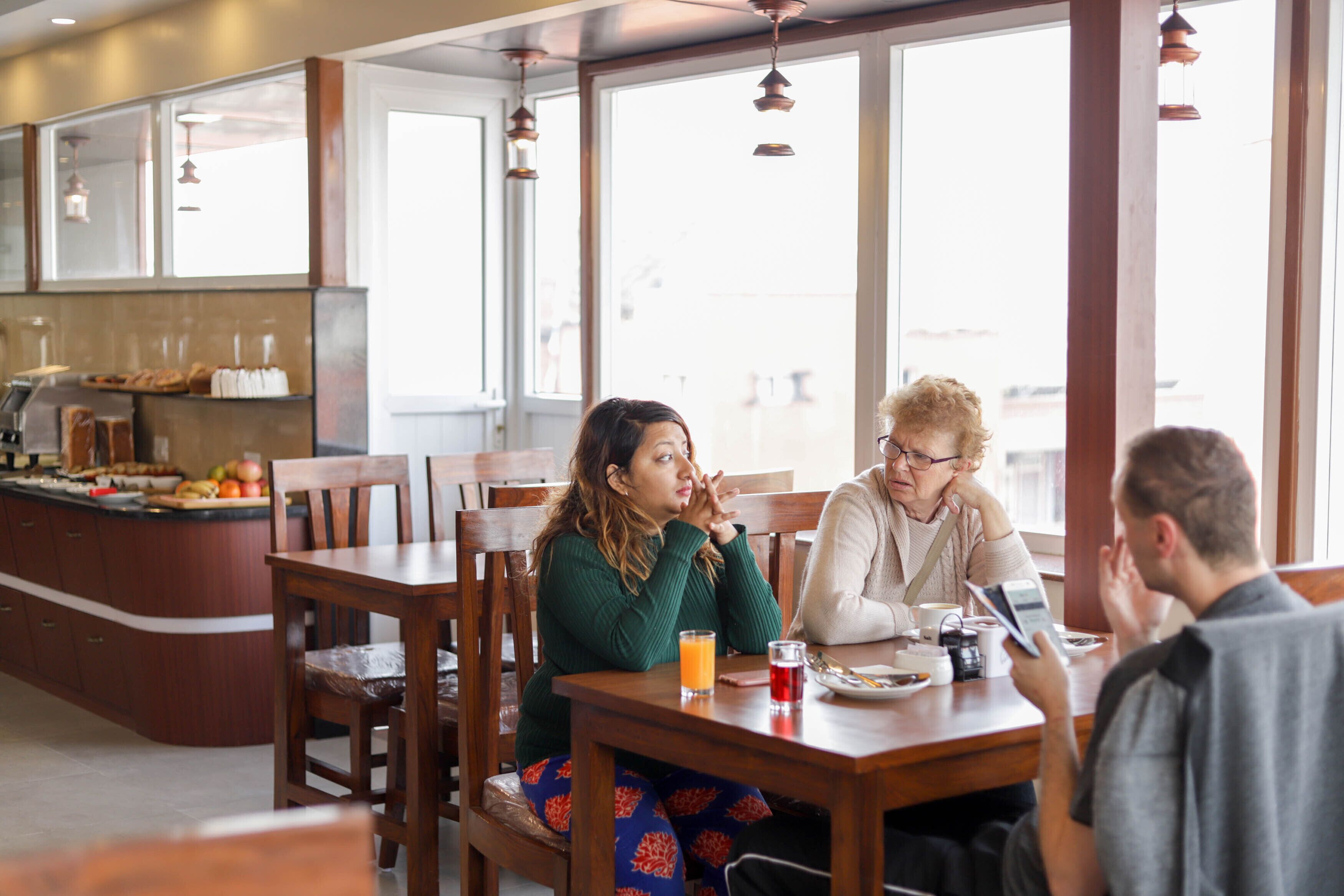 A breakfast setting with wooden furniture, a counter with food items, and large windows allowing natural light.