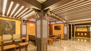 Um hall com mobiliário de madeira, um balcão de recepção e uma grande obra de arte na parede.