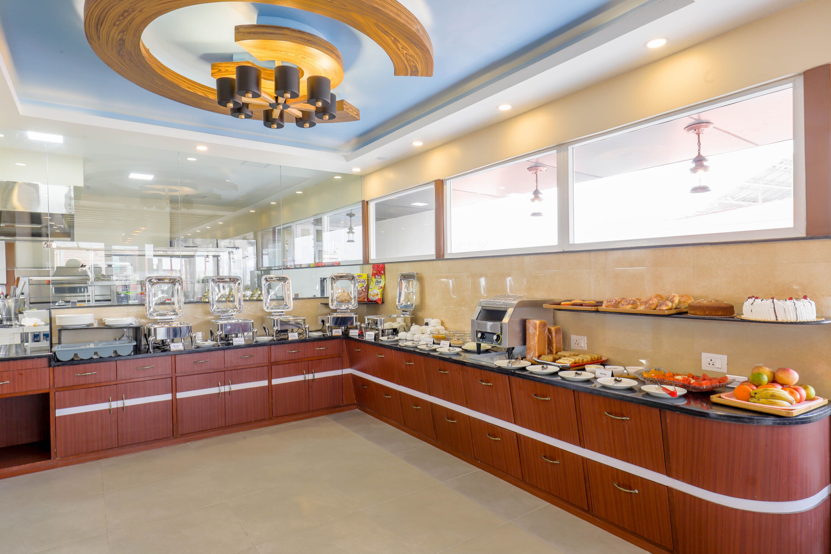 A modern kitchen with wooden cabinets, a black countertop, and a variety of food items and appliances.