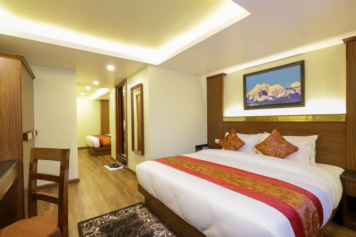Ein Hotelzimmer mit einem großen Bett, einem Holz-Kopfteil, einem Bergpanorama und einem Schreibtisch mit Stuhl.