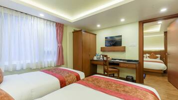 Habitación de hotel con dos camas, un escritorio con silla, un armario y un cuadro en la pared.