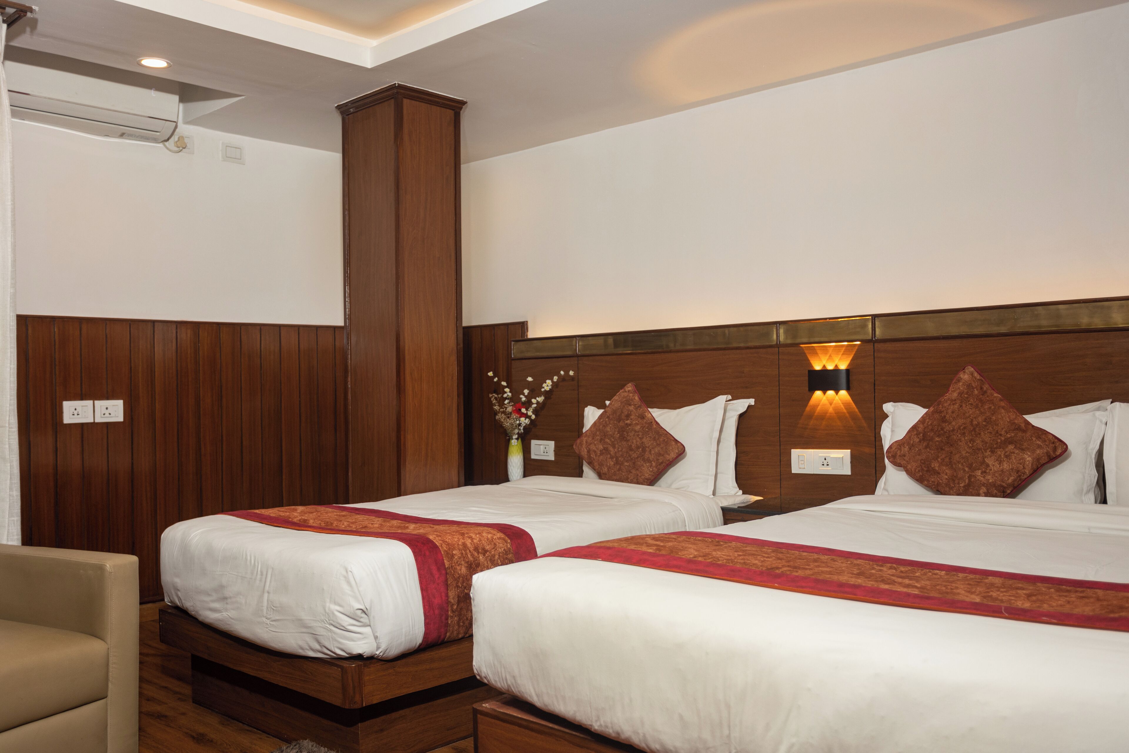 Een hotelkamer met twee bedden, houten hoofdeinden en wandlampen.