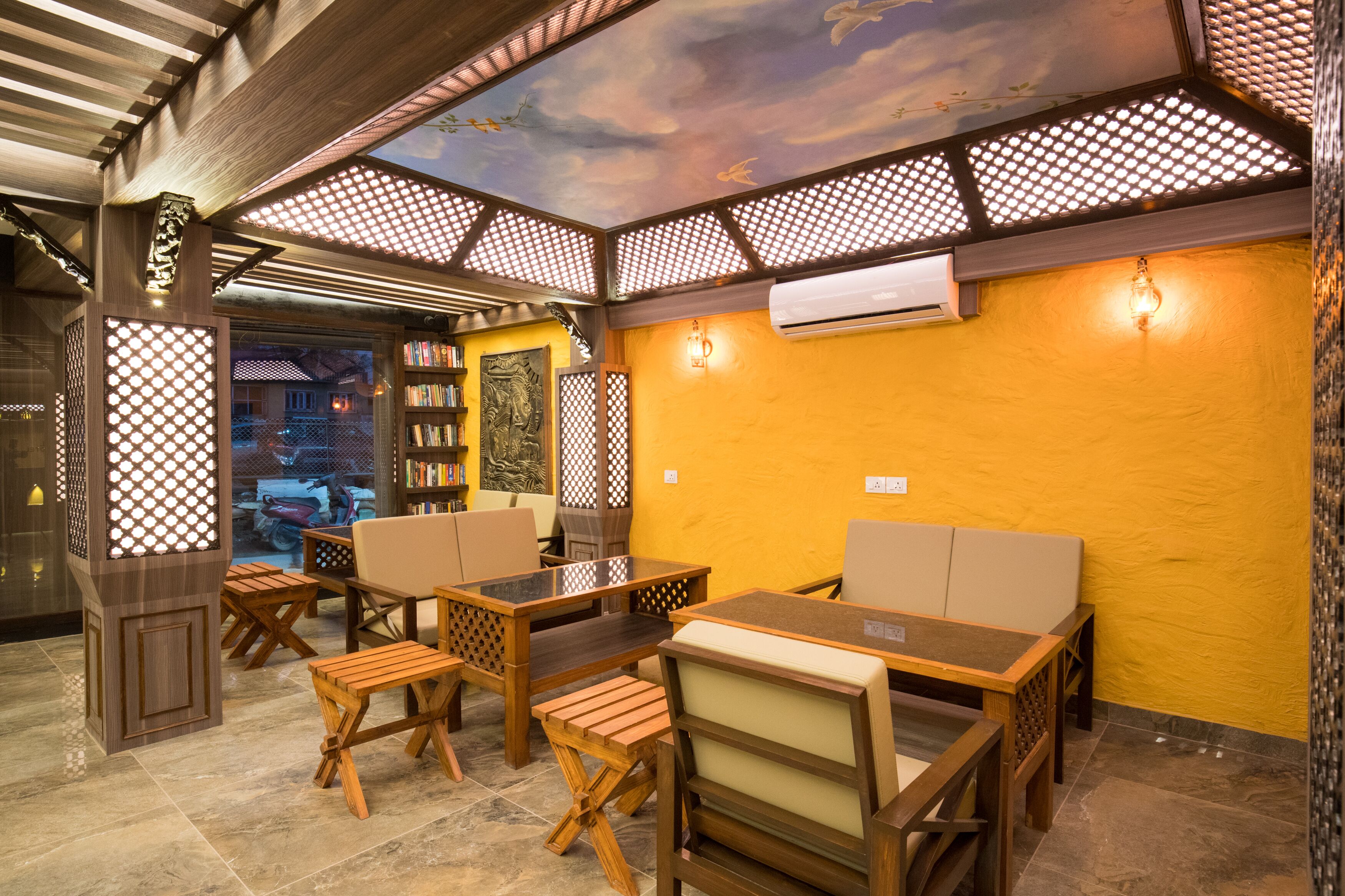 A restaurant with wooden furniture, a yellow wall, and a ceiling with a decorative pattern.