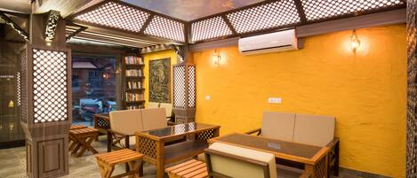 A restaurant with wooden furniture, a yellow wall, and a ceiling with a decorative pattern.