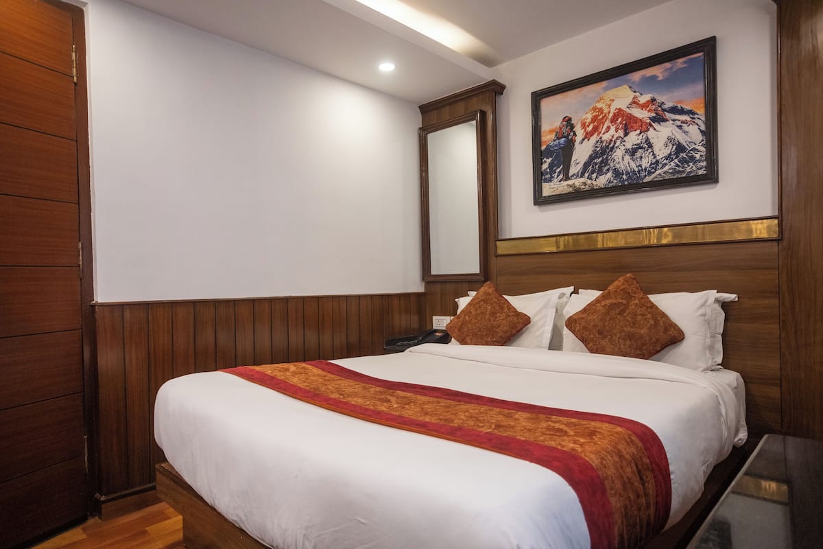 Ein Hotelzimmer mit einem großen Bett, Holzvertäfelung, einem Bergpanorama und einem hölzernen Kopfteil.