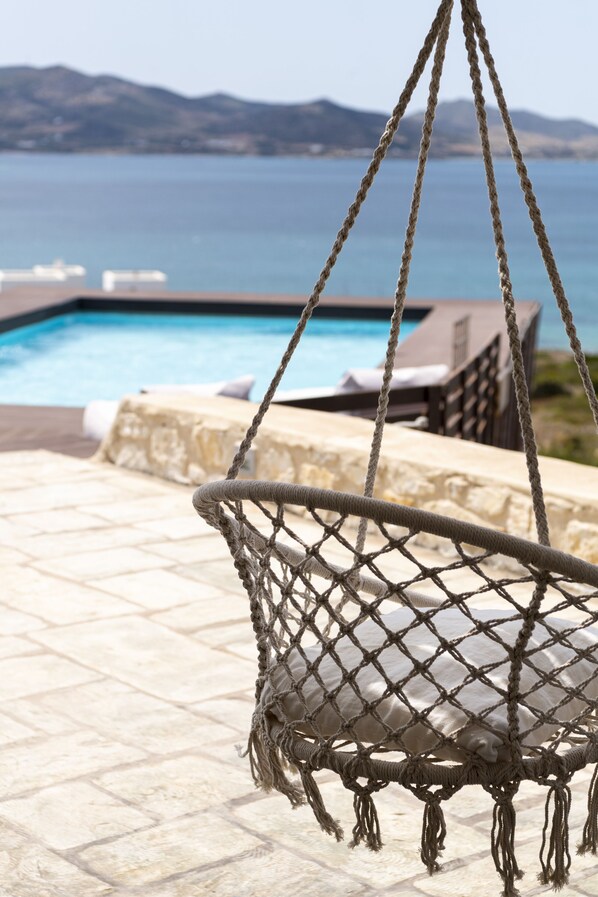 A rope swing chair overlooking a pool with a mountainous backdrop. - Villa Alenia Paros (Paros)