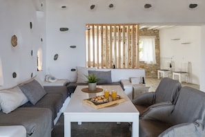 A modern living room with a sofa, a coffee table with a tray of cookies and glasses of orange juice, and a stone wall in the background.