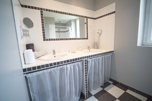 Een badkamer met twee wastafels, een grote spiegel en een handdoekrek.