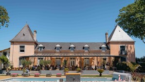 A large building with a covered patio area, a swimming pool, and outdoor seating. - Domaine St Ferreol (Chis)