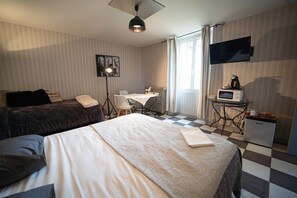 Een hotelkamer met twee bedden, een eettafel, een televisie, een koelkast en een raam met gordijnen.