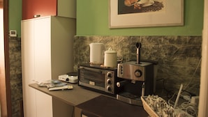 Een keuken met een broodrooster, een koffiezetapparaat en een ingelijst schilderij aan de muur.