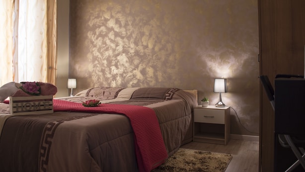 Een slaapkamer met een bed, nachtkastjes, een lamp en een televisie.
