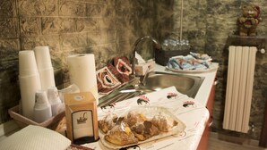 Een keuken met een achterwand van steen, een spoelbak en een aanrecht met etenswaren en wegwerpbekers.