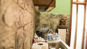 Een badkamer met een stenen muur, een houten kastje, een teddybeer decoratie en toiletartikelen.