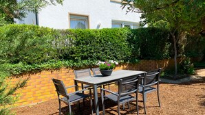 An outdoor patio with a table and chairs, surrounded by a brick wall and greenery. - WeinheimResidence (2) (Weinheim)