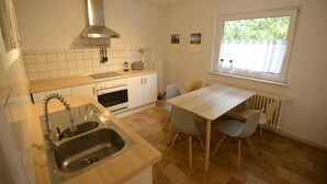A compact kitchen with a sink, stove, and window overlooking greenery. - WeinheimResidence (2) (Weinheim)