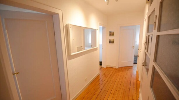 A hallway with wooden flooring, white walls, and doors leading to other rooms. - WeinheimResidence (2) (Weinheim)