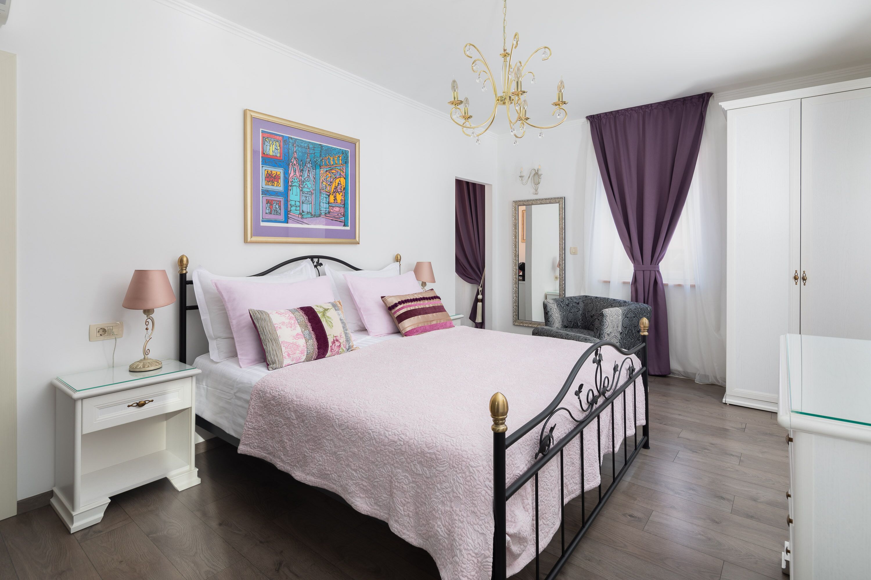 A bedroom with a bed, nightstand, dresser, and a large mirror.