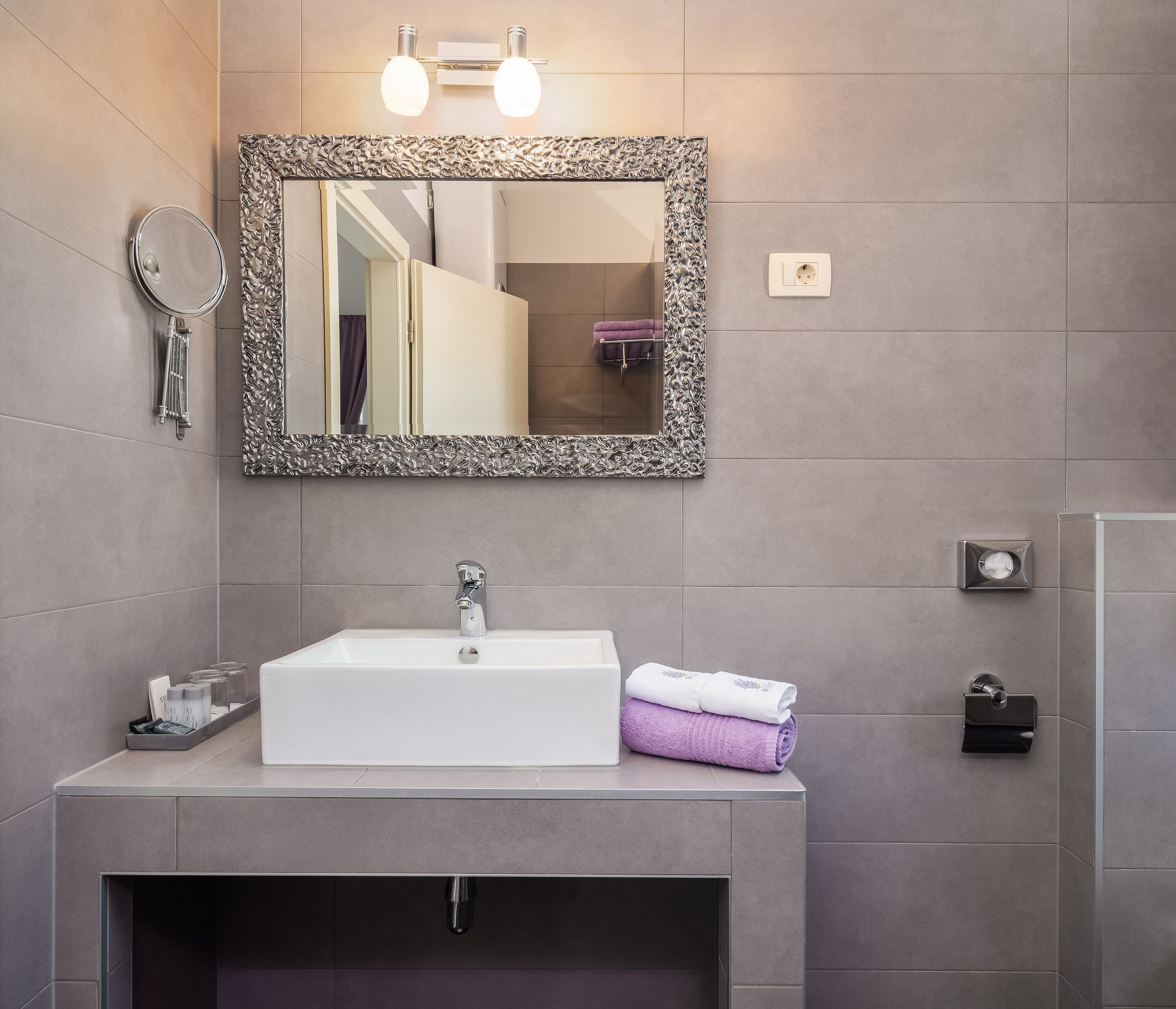 A bathroom with a white sink, a mirror with an ornate frame, and a towel rack with towels.