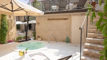 Relax in an outdoor oasis with a hot tub, seating area, and lush greenery.