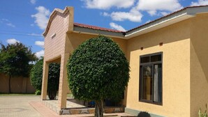 Um edifício com fachada amarela, telhado de telhas vermelhas e uma grande janela.