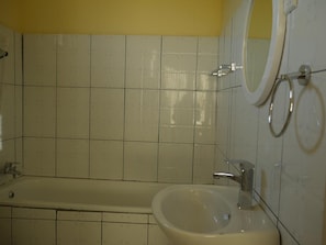 A bathroom with a bathtub, a sink, and a mirror.