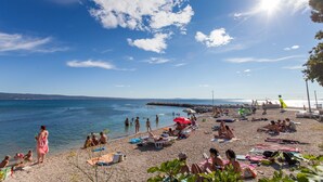 Nær stranden, hvit sand, solsenger og parasoller