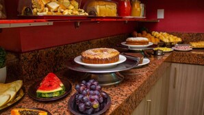 Een buffet met diverse gerechten, waaronder taart, brood en fruit zoals watermeloen en druiven.