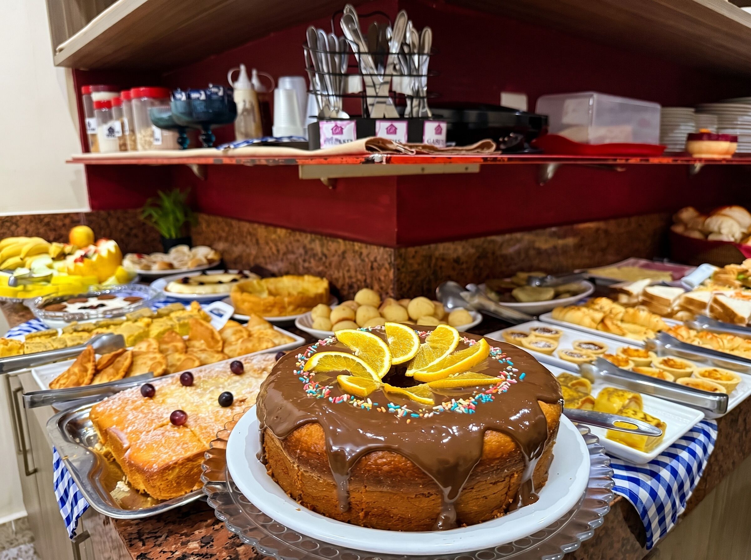 A buffet with a variety of food items, including a chocolate cake with orange slices on a white plate.