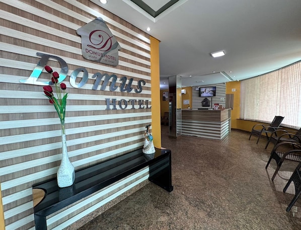 A reception area with a sign reading "DOMUS HOTEL" and a reception desk.