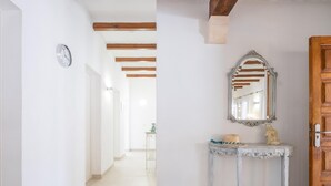 A hallway with a white console table, a mirror, and a wooden door. - Villa Can Odile By SunVillas Mallorca (Cala San Vicens)