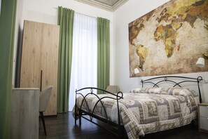 A bedroom with a bed, a desk, a chair, a map on the wall, and a window with curtains. - B&B A casa da Gabry (Catania)