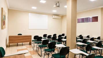 A classroom with rows of desks and chairs, a podium, and a projector screen.