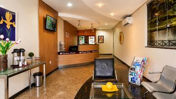 Zona de recepción de un hotel con mostrador, asientos y vista al exterior.