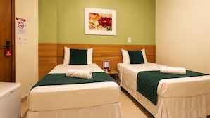 A hotel room with two beds, a nightstand, a painting, and a door with a fire alarm. - Domus Hotel Veneza - Ipatinga (Ipatinga)