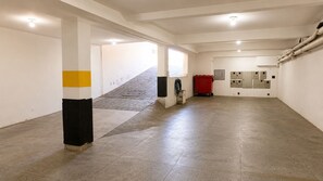 A spacious corridor with a tiled floor, white walls, and a staircase leading to an upper level.