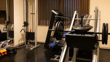 A gym with exercise equipment, a weight bench, and a mirror.