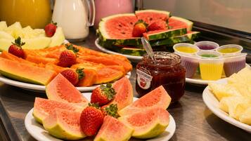 A variety of fruits and a jar of jam on a table.