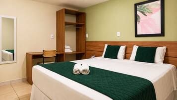 Quarto de hotel com cama, guarda-roupa de madeira, uma cadeira e um quadro na parede.