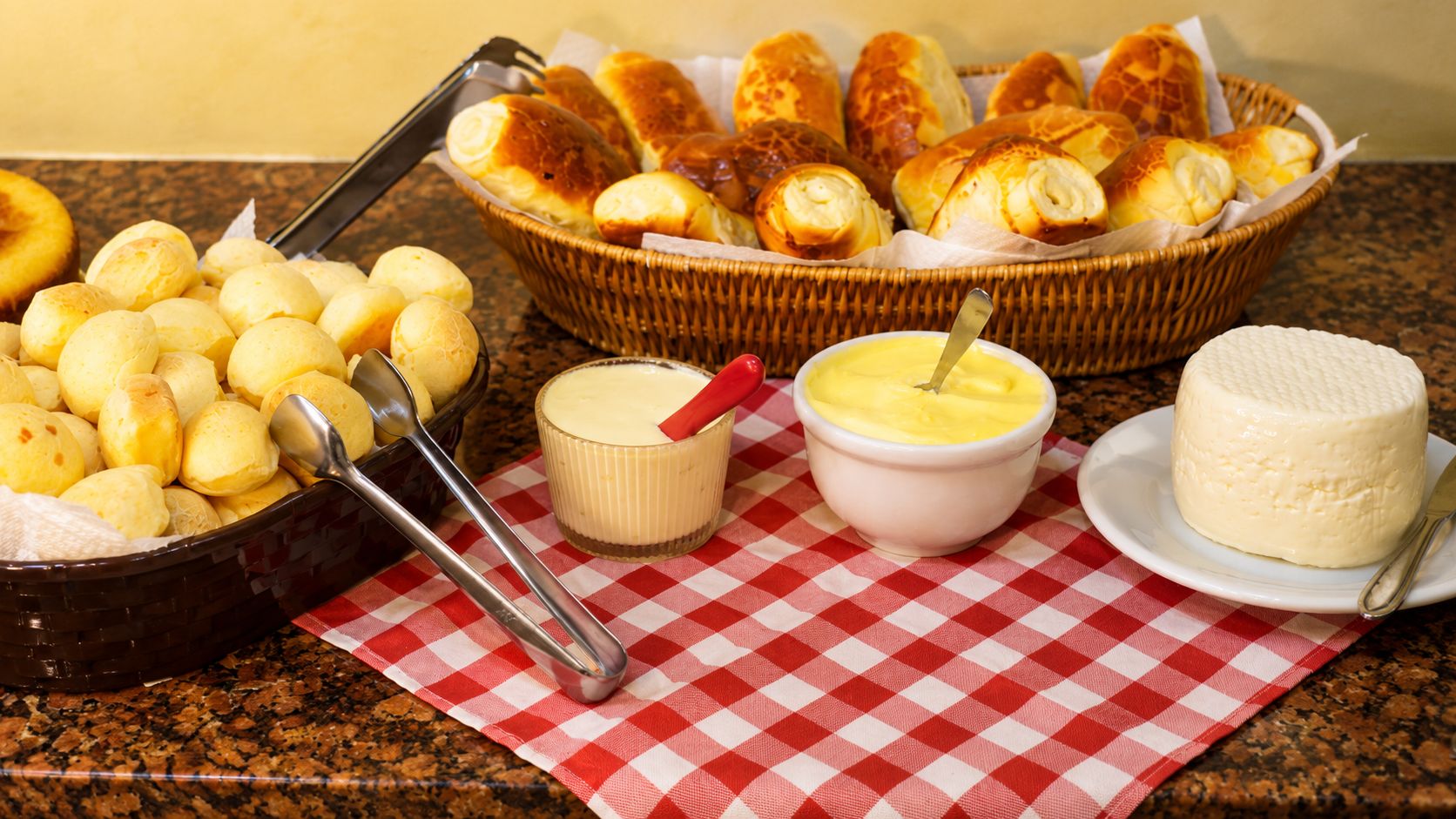 Una mesa de bufé con diversos alimentos, incluyendo pan, queso y un bol de salsa.