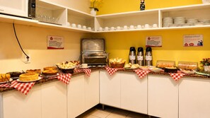 Disposición de bufé con diferentes opciones de comida, una estación de café y un microondas.
