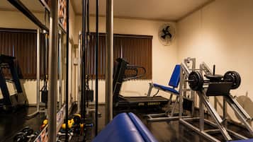 Un gimnasio con equipamiento de ejercicio, una cinta de correr y un banco de pesas.