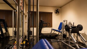 Academia com equipamentos de ginástica, esteira e banco de musculação.